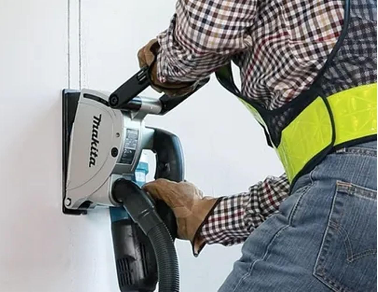 Person using a Makita power tool on a white background
